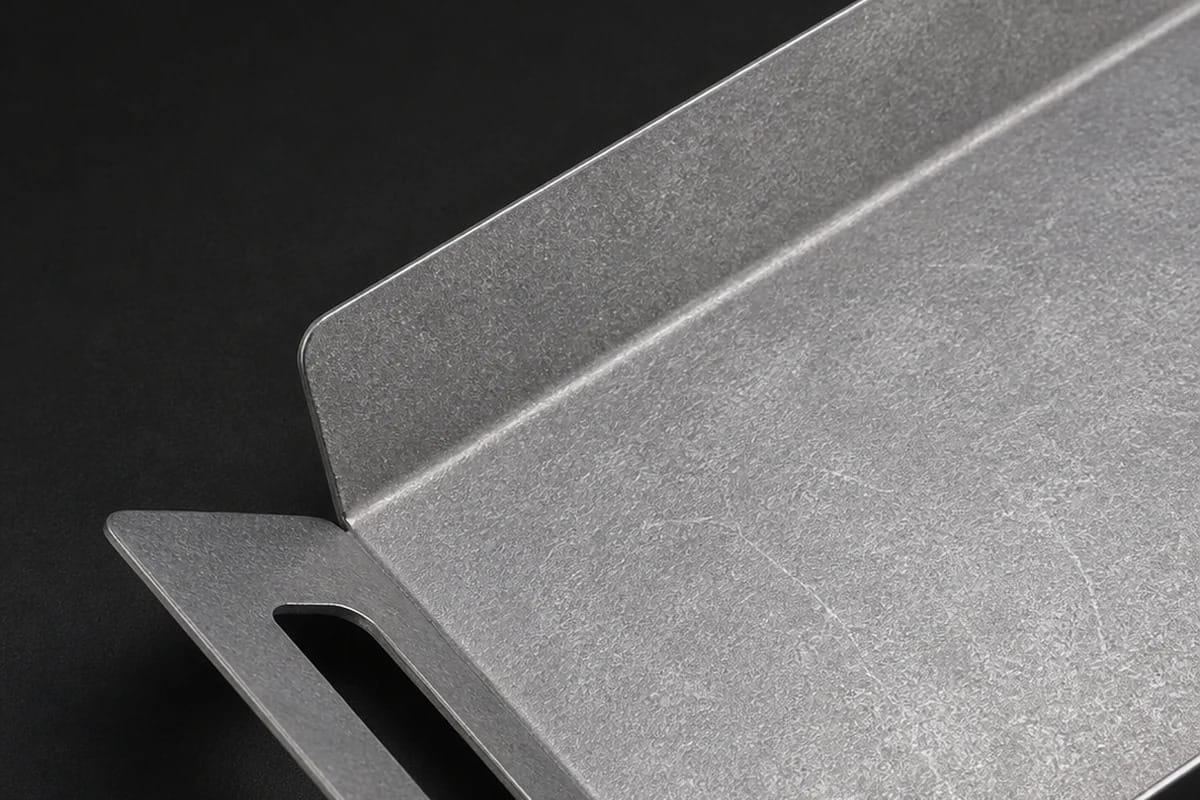Close-up of the mottled surface and integrated cutout handle of the vintage metal tray